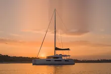 Ein Katamaran in der Dämmerung vor Anker, der Himmel orange