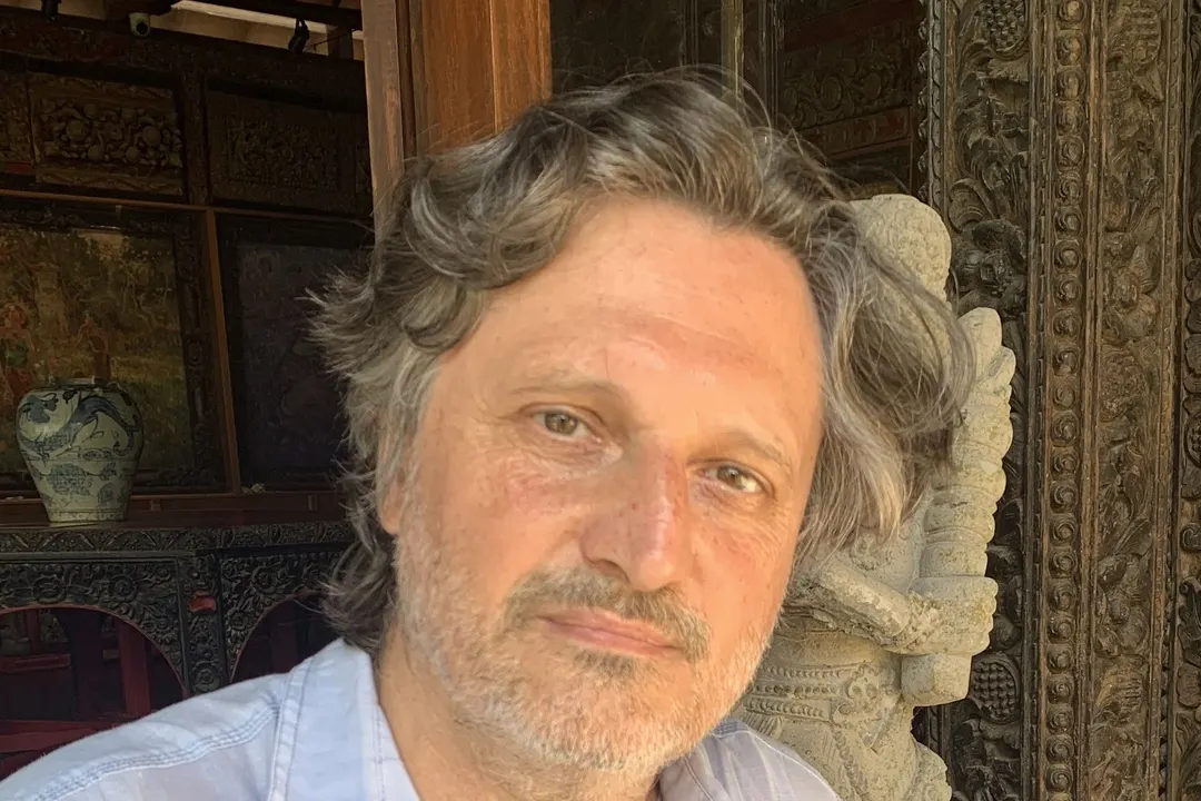 Adrian Constantinescu, Porträt vor grünem Laub, im hellen Leinenhemd