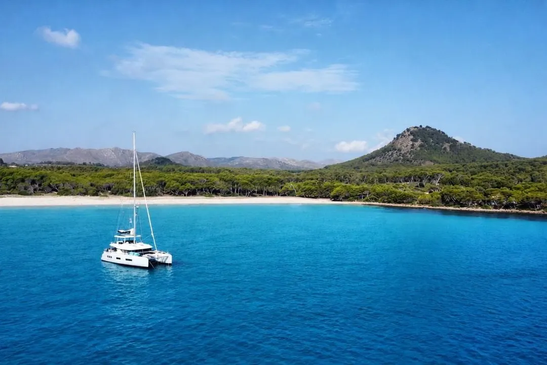 Der Katamaran allein vor Anker in einer weiten Bucht, türkisfarbenes Wasser, bewaldete Hügel dahinter